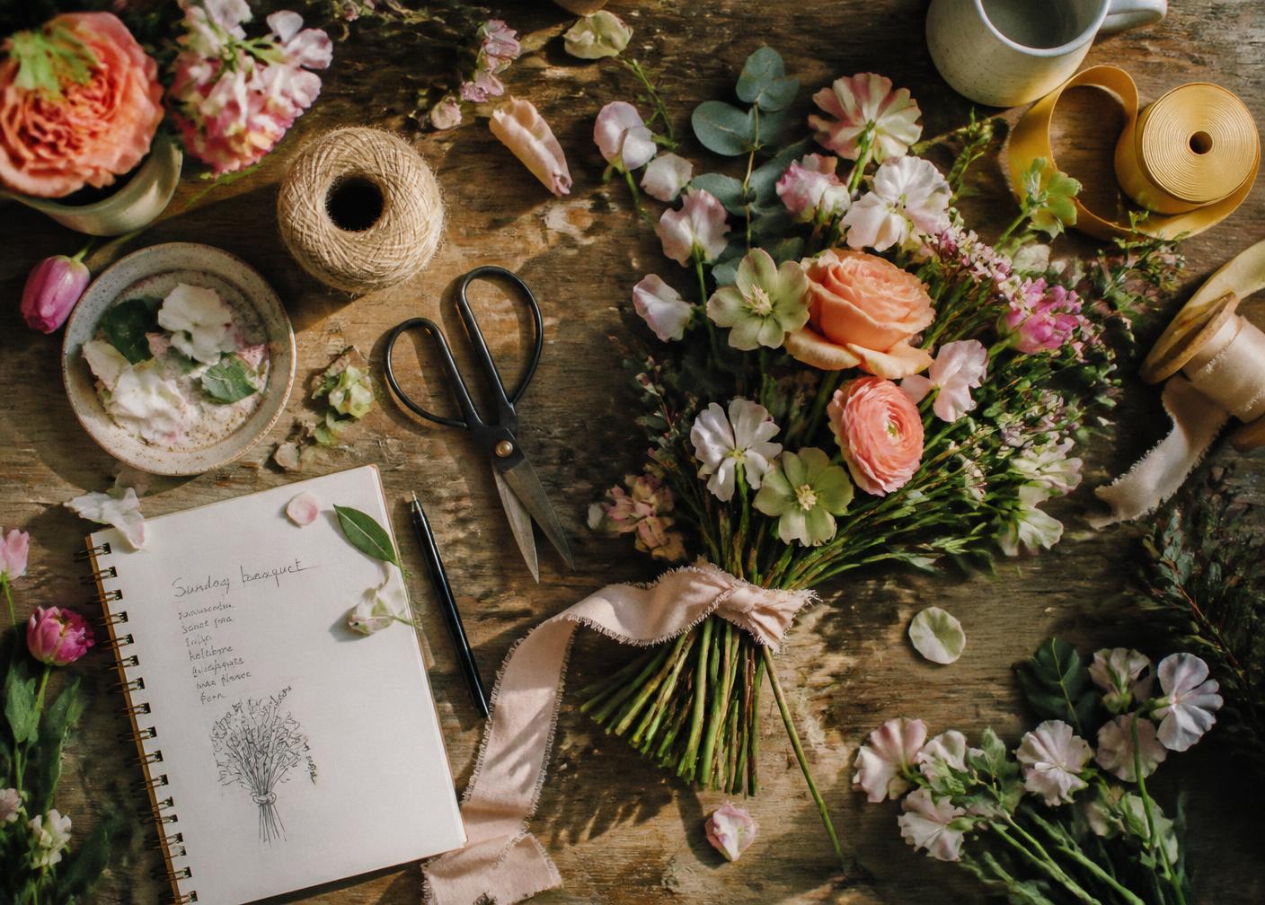 Mesa de trabajo del taller con tijeras, cintas y flores a medio montar