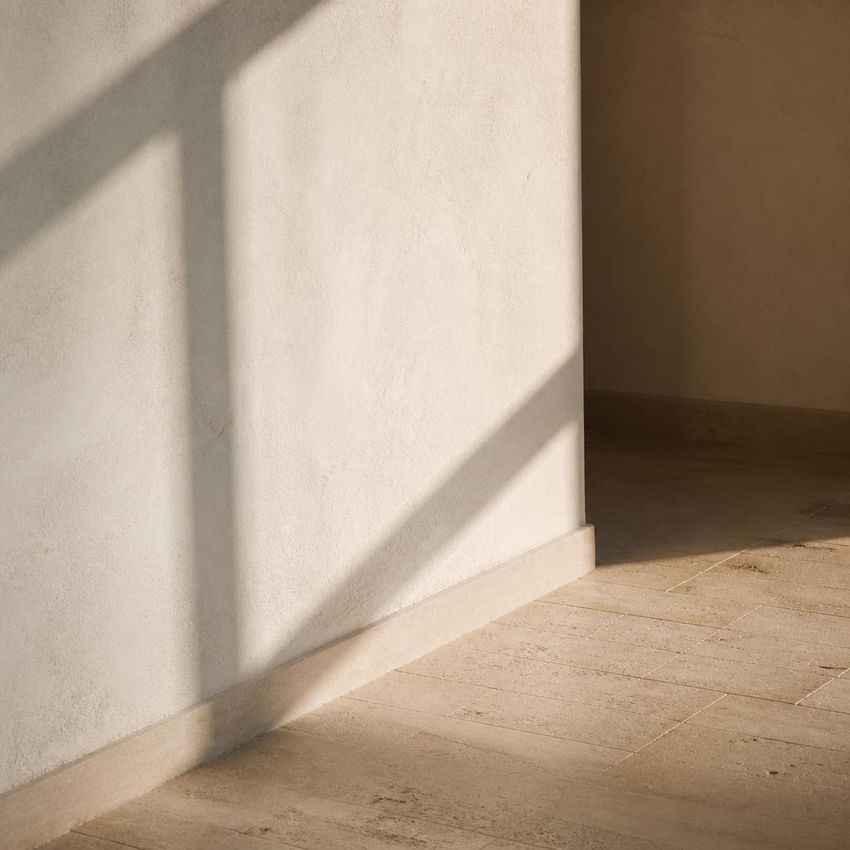 Luz natural proyectando la sombra de una ventana sobre una pared de cal